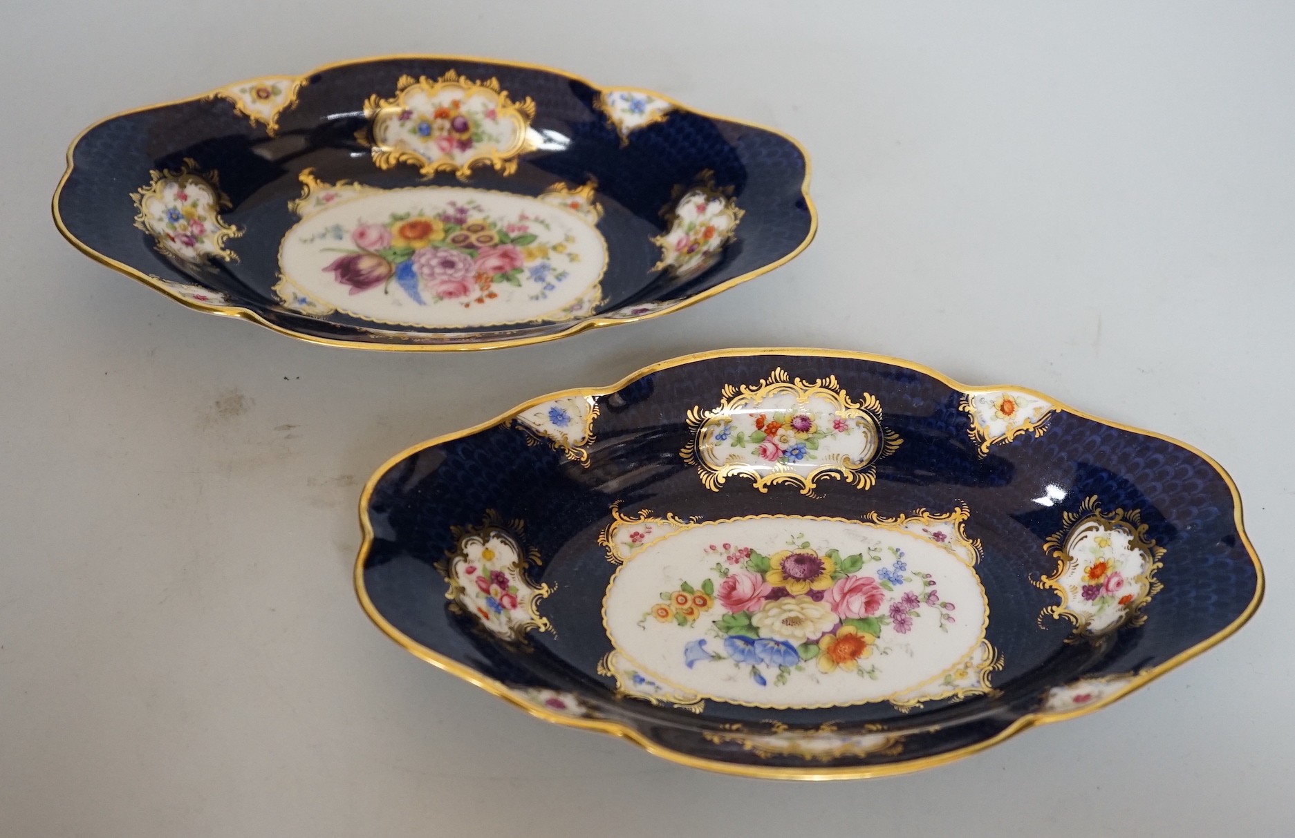 A pair of Royal Worcester blue ground floral painted dishes by E Phillips, signed date code for 1894, length 21cm